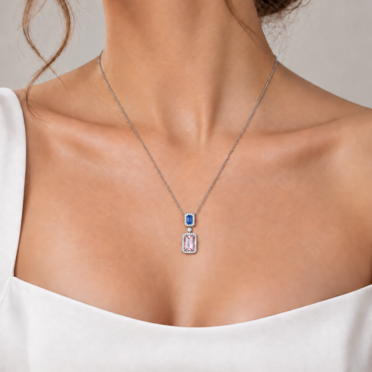 18K white gold drop pendant necklace featuring an emerald-cut natural pink morganite and blue sapphire, each framed by sparkling natural colorless diamond halos in an elegant double-drop design.