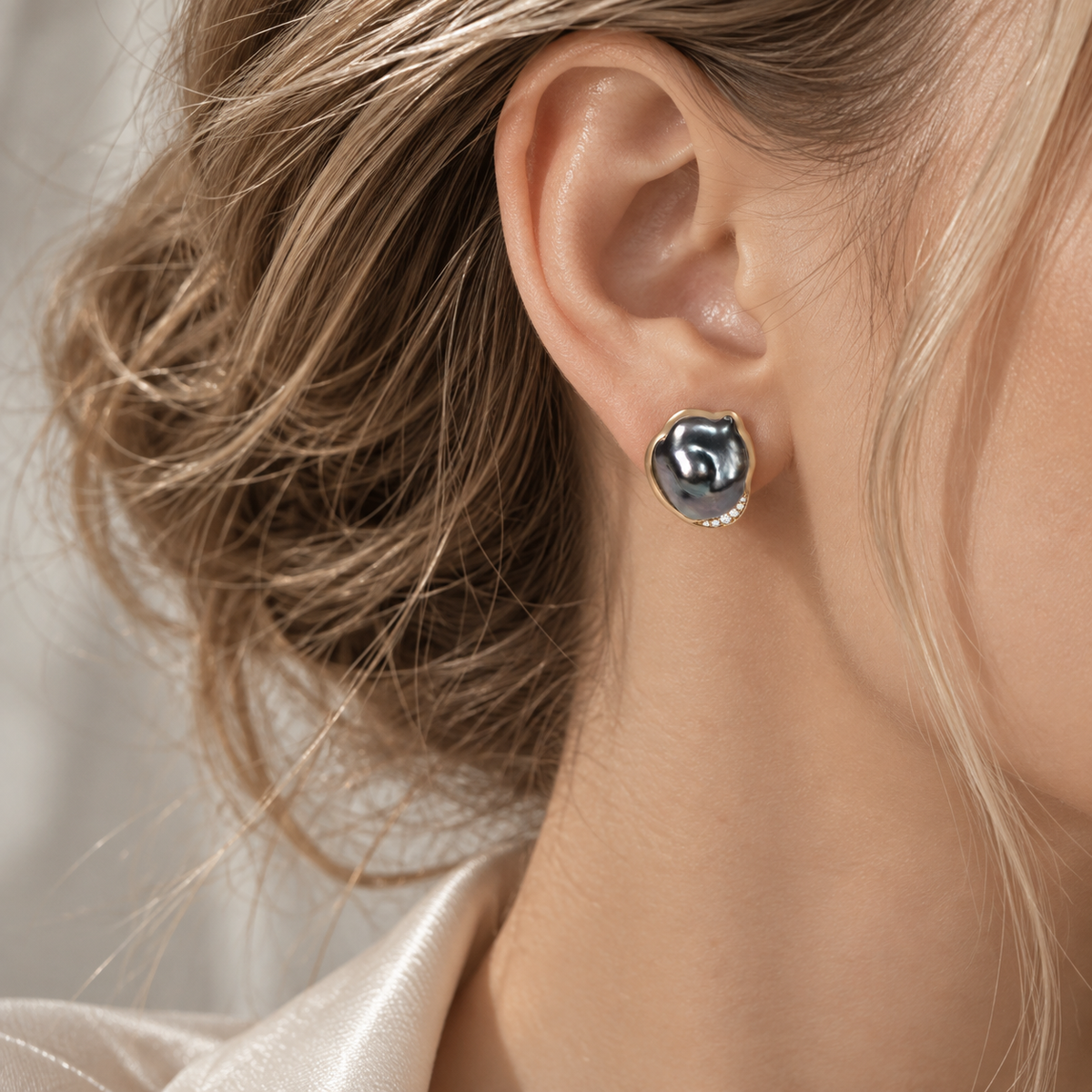 18K gold natural diamond and dark baroque pearl stud earrings featuring a sculptural pearl center accented with a delicate row of sparkling diamonds.