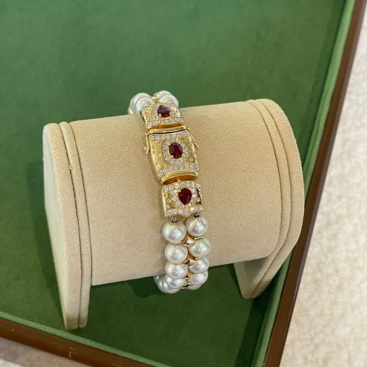 18K gold statement bracelet featuring ruby center stones, sparkling diamond accents, and lustrous white pearls, styled alongside a classic diamond tennis bracelet.