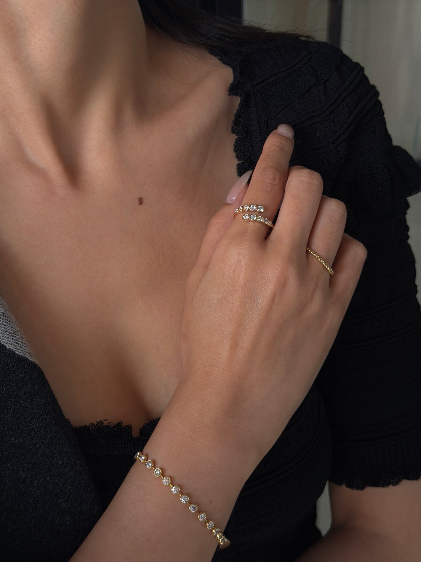Close-up of a woman modeling an 18K yellow gold open bypass ring with 0.60ctw bezel-set lab-grown diamonds on her index finger.
