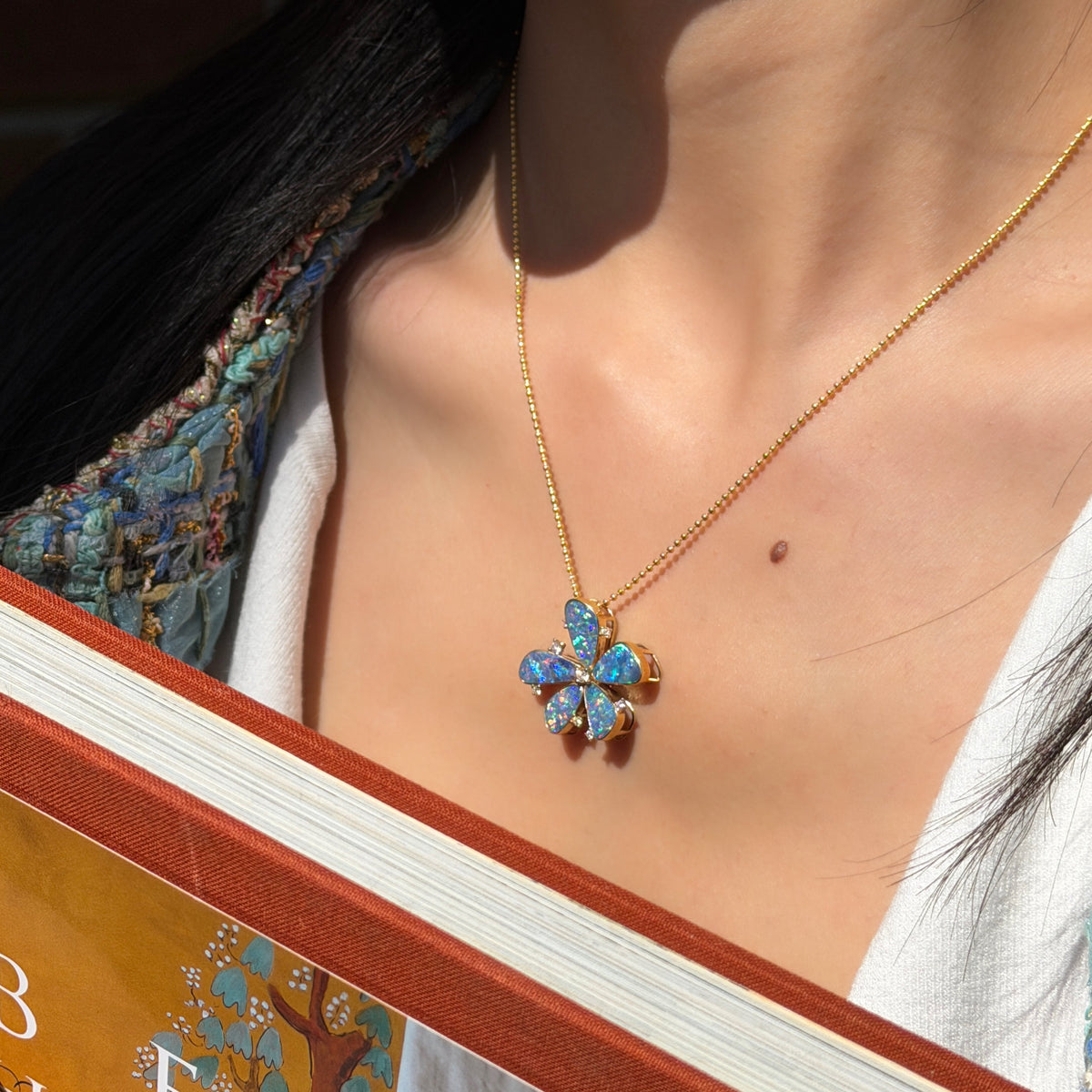 Alt Text: > Large floral pendant featuring five natural blue-green opals set in 18K yellow gold with diamond accents on a gold ball chain.
