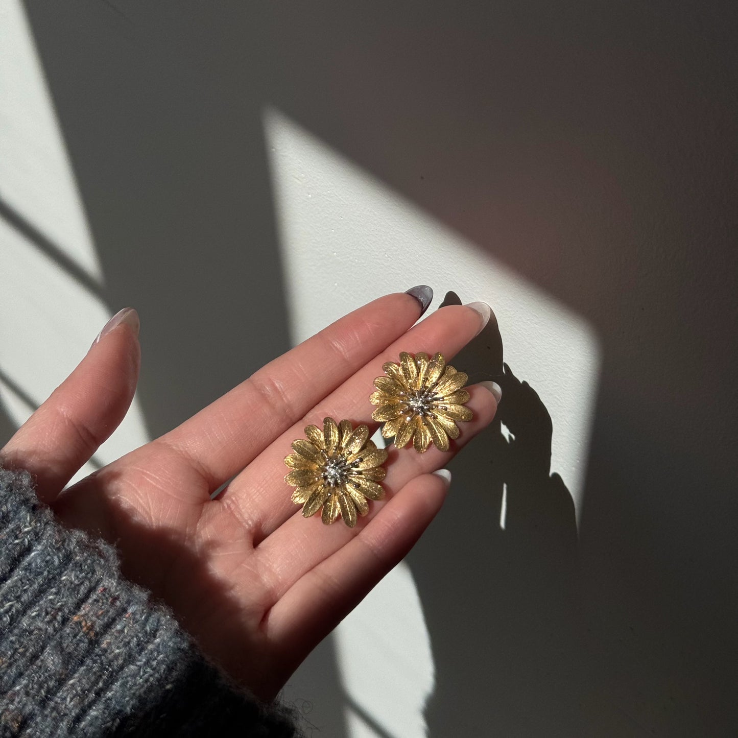 Italian silver floral earrings featuring textured gold-tone daisy petals with delicate silver centers, shown in natural sunlight.