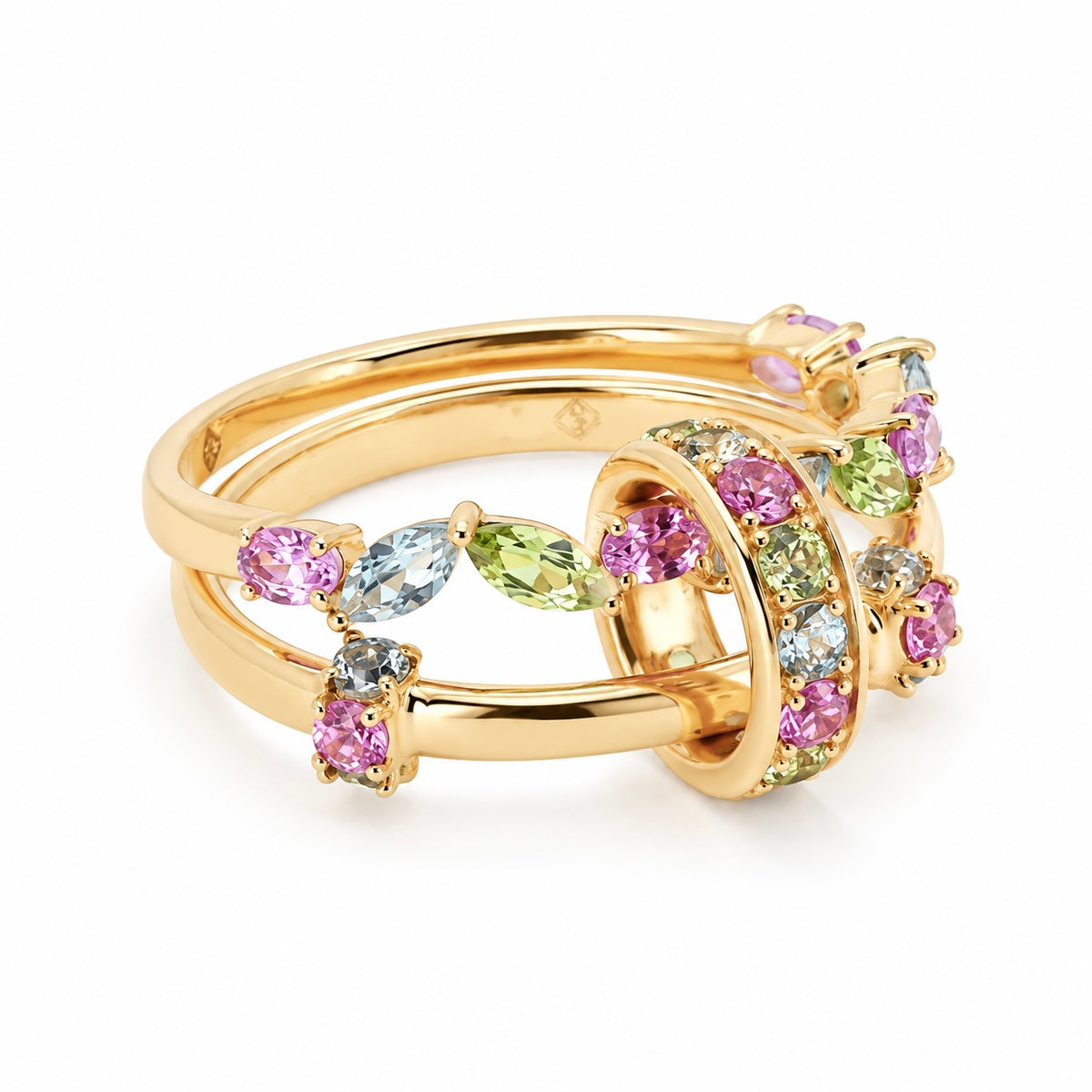 The fairy garden ring folded into a stacked, single-finger position on a white background. The two 18k yellow gold bands sit parallel, joined by a gem-encrusted center loop. A colorful cluster of pink sapphires, green peridots, and light blue aquamarines creates a magical, floral-like arrangement.