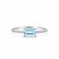 An elegant 18K white gold fine jewelry ring featuring a horizontally set emerald-cut light blue aquamarine center stone on a delicate pavé diamond band, isolated against a crisp white background.