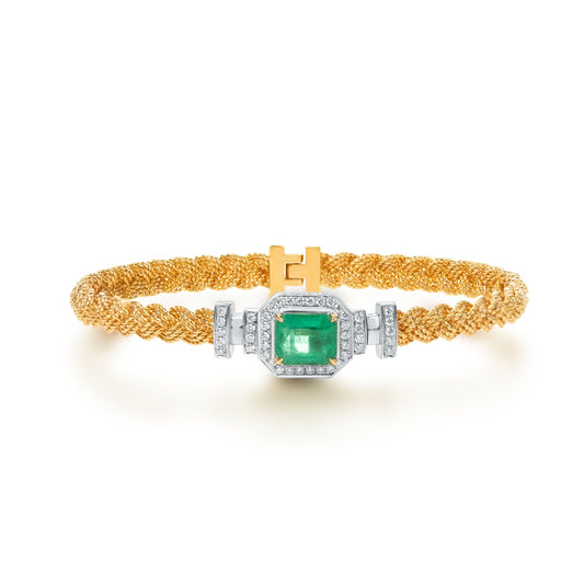 Elegant bracelet crafted in 18K yellow gold, featuring a natural emerald center stone surrounded by colorless natural diamonds. The woven gold chain design adds texture and flexibility for comfortable everyday wear. All gemstones are natural and untreated.