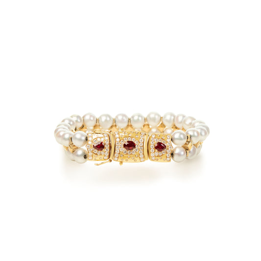 Elegant bracelet featuring natural pearls, accented with ruby center stones and colorless natural diamonds, set in 18K yellow gold. A refined design that blends classic pearls with vibrant gemstones.