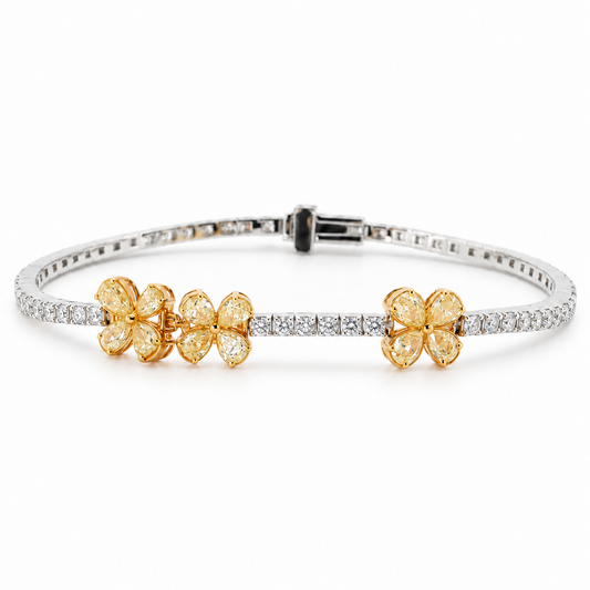 18K white and yellow gold natural diamond bracelet featuring pear-shaped yellow diamonds arranged in three floral clusters, accented with a sparkling row of round brilliant-cut white diamonds.