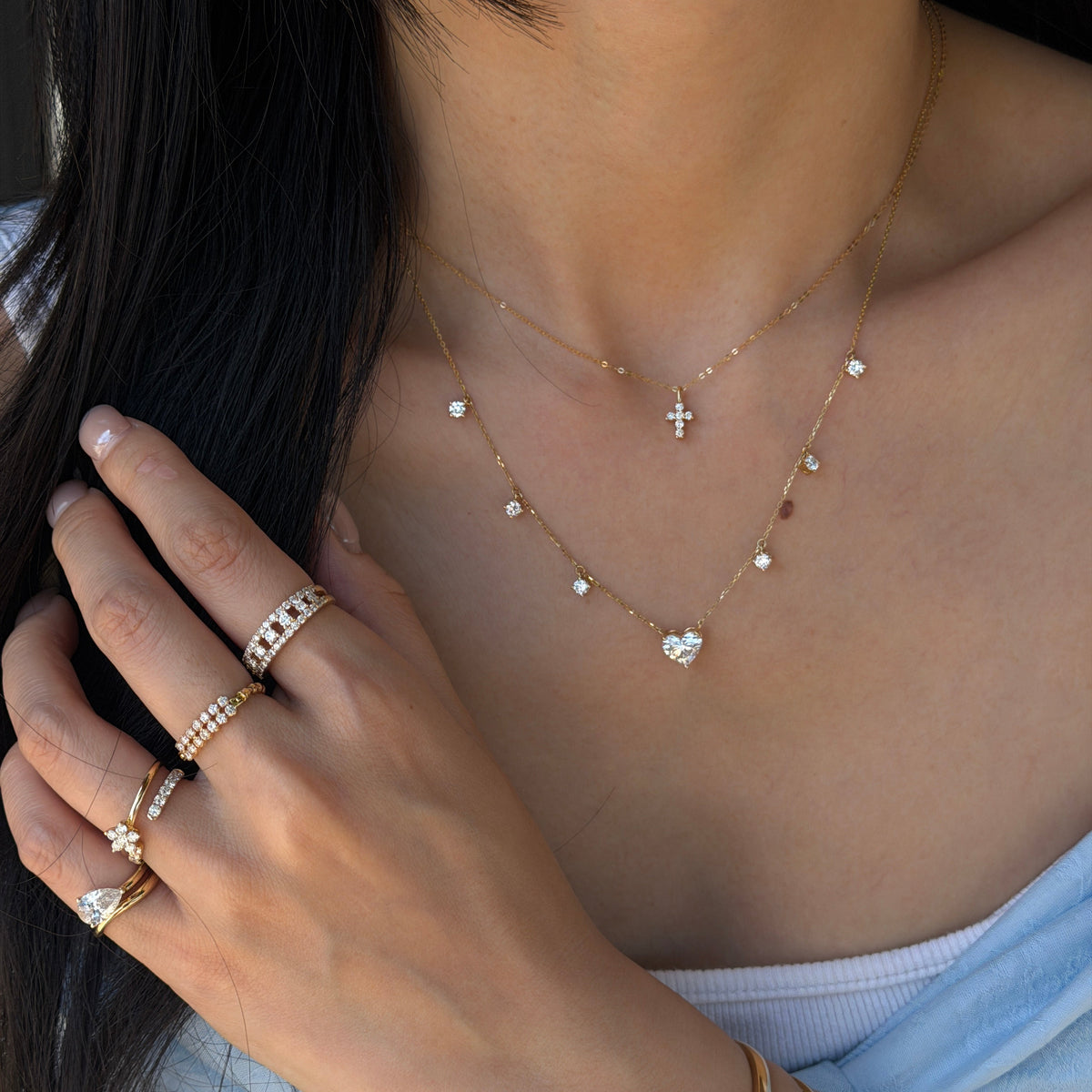 18K gold mini cross necklace featuring sparkling natural diamonds, layered with a natural diamond heart pendant and delicate diamond station chain.