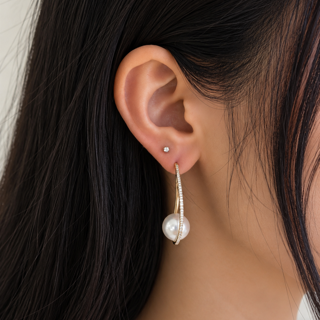 18K gold drop earrings featuring a lustrous Australian White South Sea pearl accented by a graceful curved line of natural diamonds in an elegant contemporary design.