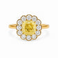 Front view of a Fantasilvia 18K yellow gold ring featuring a large cushion-cut fancy yellow diamond center stone surrounded by a flower-shaped halo of round white diamonds on a white background.