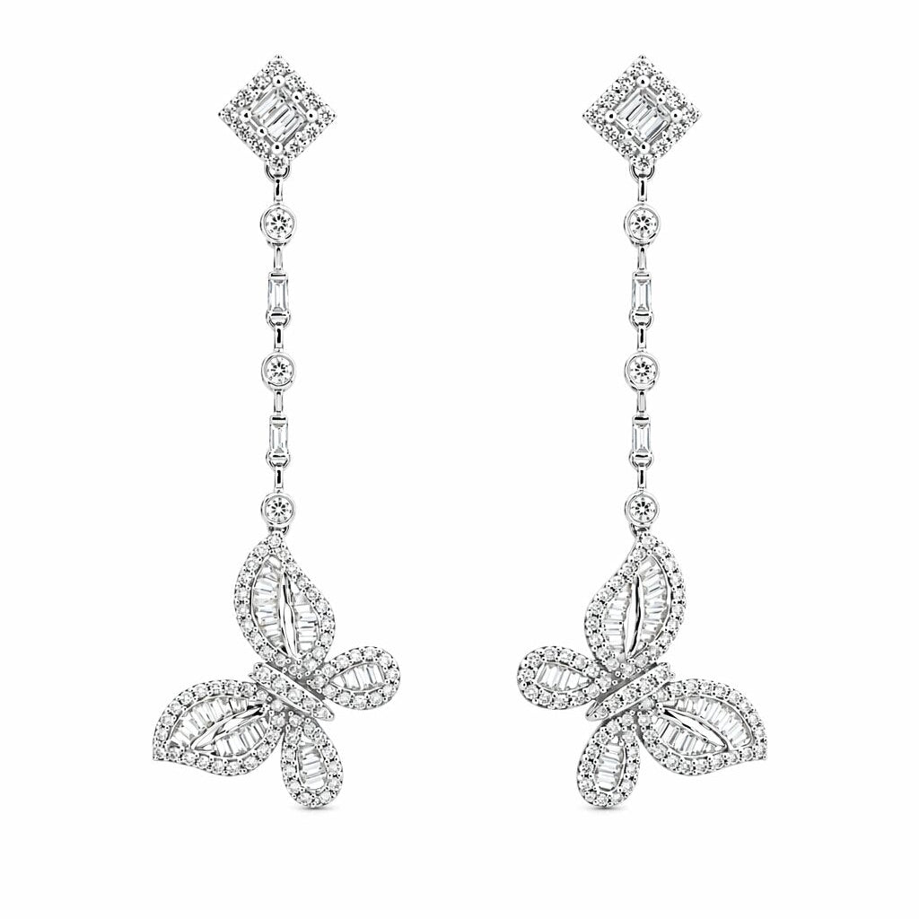 A pair of 18K white gold diamond drop earrings against a white background. Each earring features a diamond-shaped stud, a linear drop chain of alternating round and baguette diamonds, and a detailed butterfly pendant at the base set with a mix of round and baguette-cut diamonds.