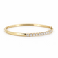 18K yellow gold hinged bangle featuring a row of round brilliant diamonds accented by a princess cut diamond at the terminal.