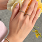 The Fairy Garden kinetic ring worn opened across two fingers. The bespoke 18k gold ring features a movable center loop and colorful gemstones.