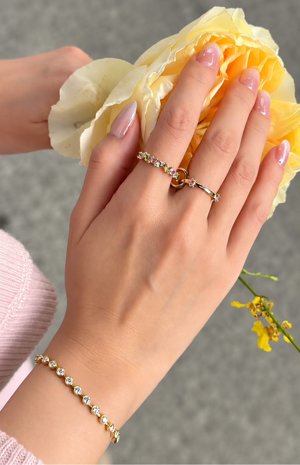 The Fairy Garden kinetic ring worn opened across two fingers. The bespoke 18k gold ring features a movable center loop and colorful gemstones.