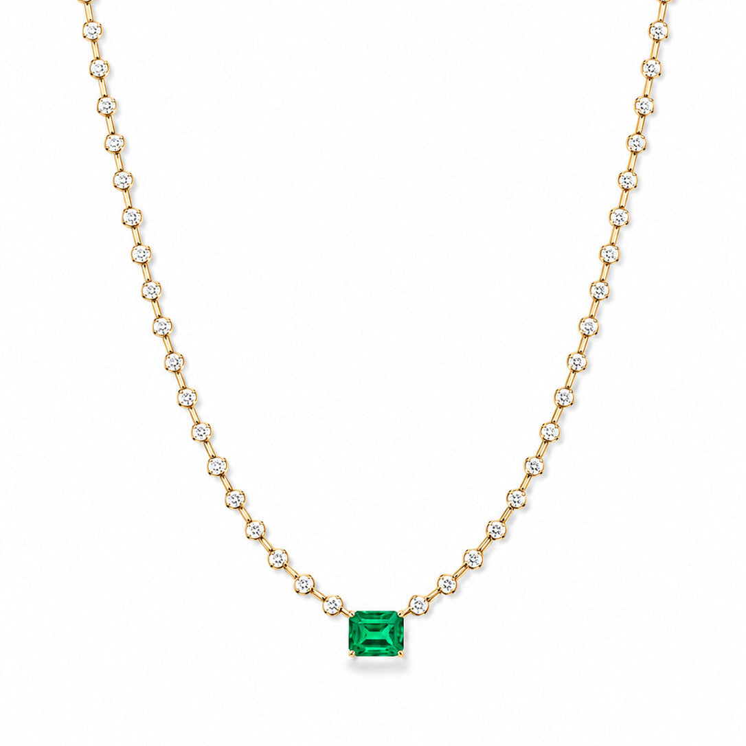 A Fantasilvia necklace featuring a central rectangular emerald-cut emerald suspended from a continuous strand of round-cut diamonds in 18K yellow gold settings on a white background.