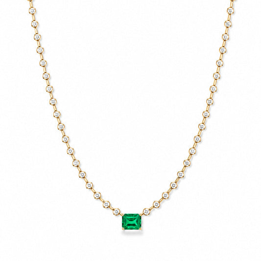 A Fantasilvia necklace featuring a central rectangular emerald-cut emerald suspended from a continuous strand of round-cut diamonds in 18K yellow gold settings on a white background.