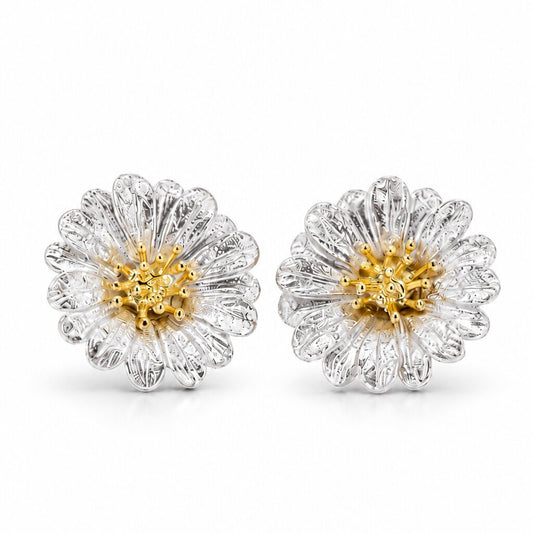 A pair of silver stud earrings shaped like blooming daisies, featuring intricately textured petals and a contrasting gold-colored center, displayed against a white background.