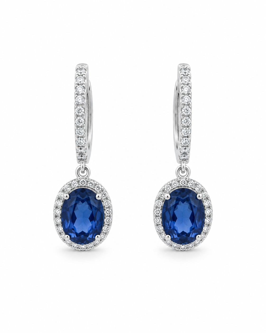 Front view of 18K white gold drop earrings featuring oval natural blue sapphires surrounded by colorless diamond halos on a white background.