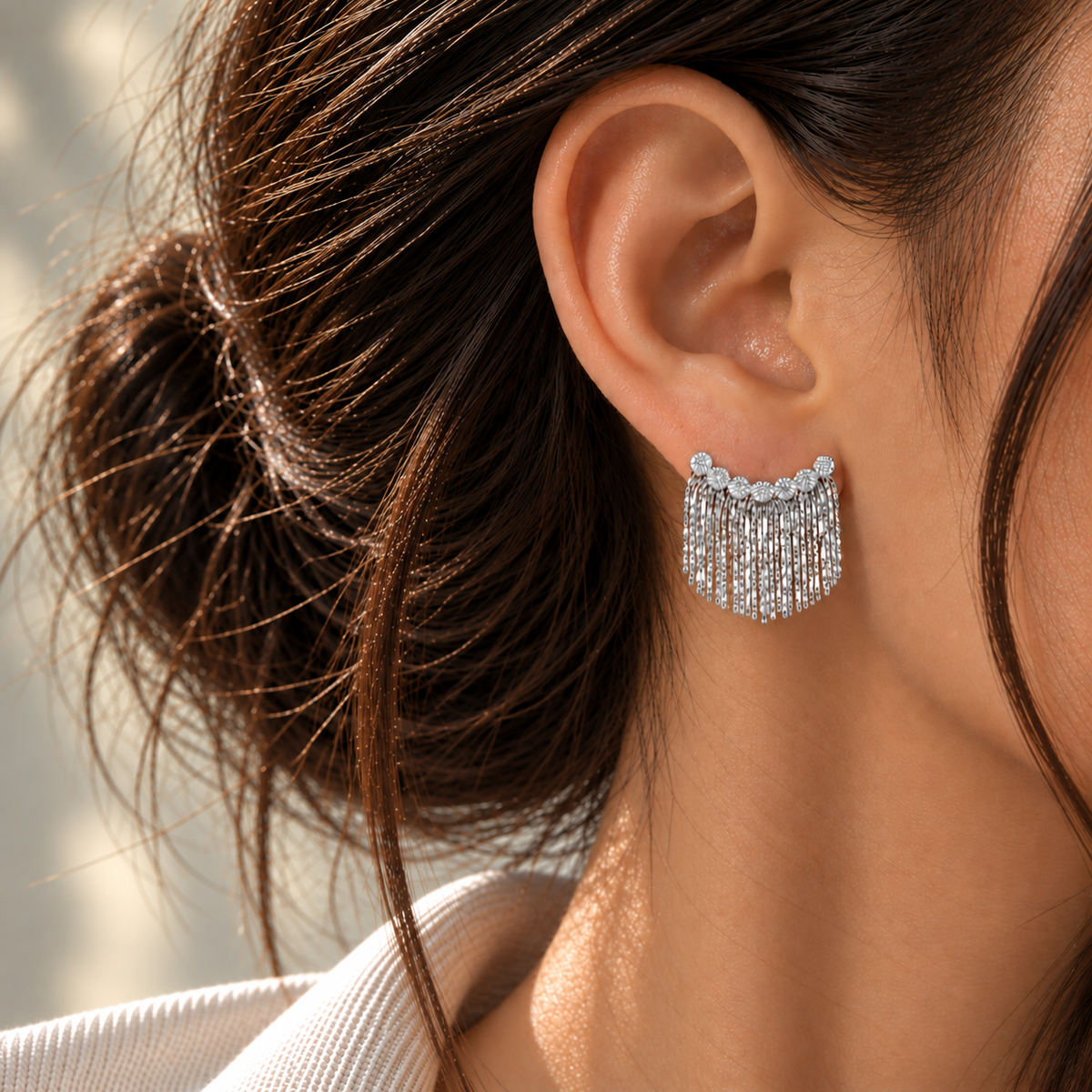 18K white gold fringe earrings featuring a sculptural cascading chain design with textured circular accents, styled on the ear.