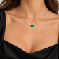 18K yellow gold necklace featuring a rectangular natural emerald centerpiece accented with a continuous row of sparkling round diamonds in an elegant station-style design.