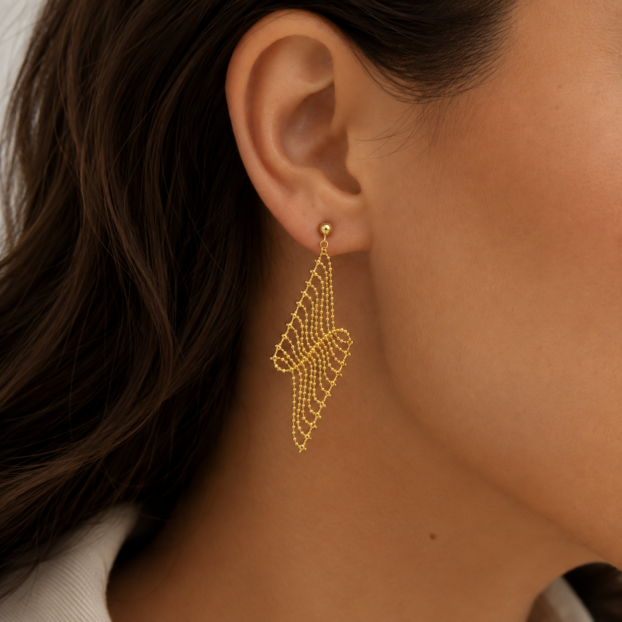Italian silver drop earring with a gold-tone finish, featuring an intricate cascading mesh and chain design, styled on the ear.