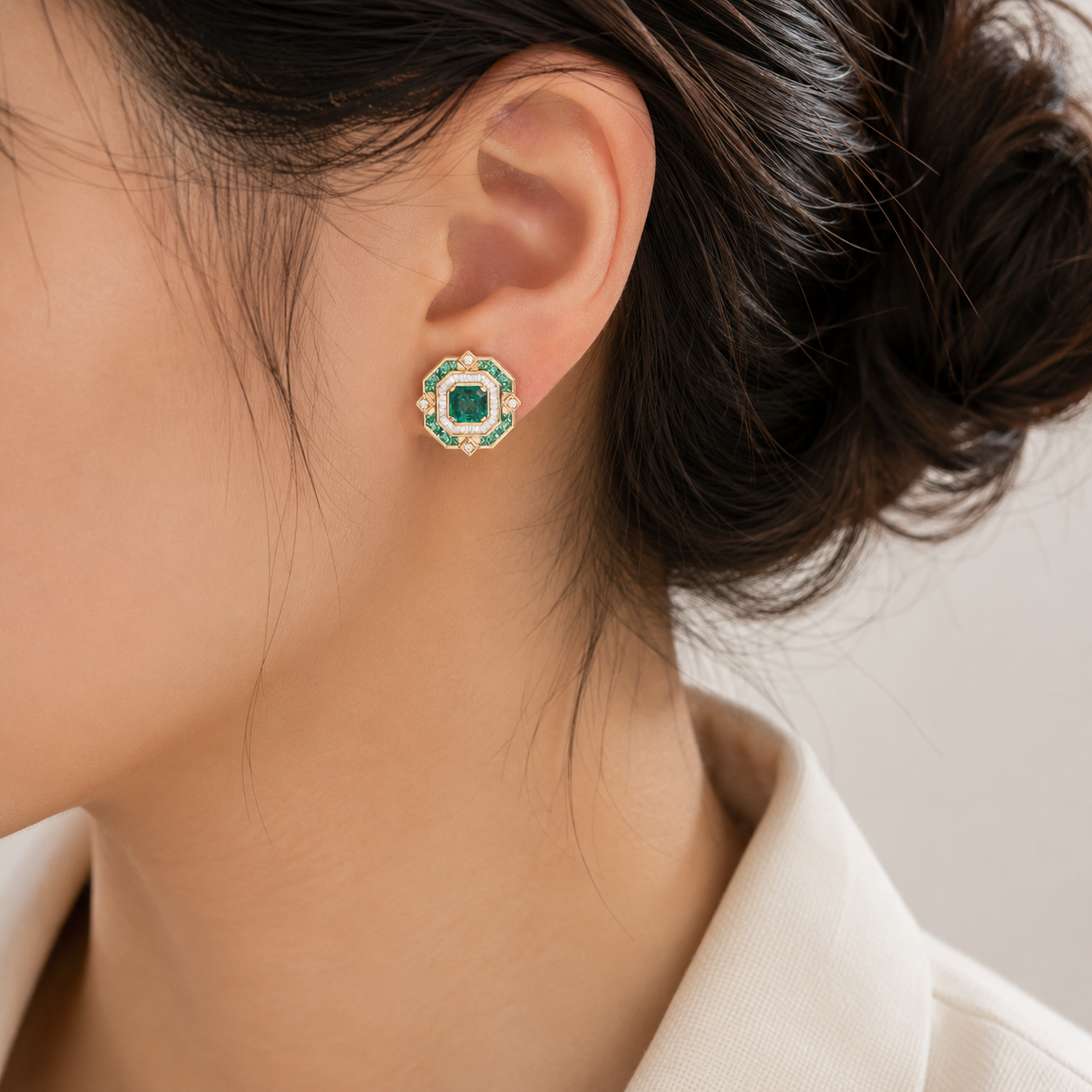 18K gold emerald stud earring featuring a square-cut natural emerald surrounded by emeralds and sparkling natural diamonds in a geometric Art Deco-inspired design.