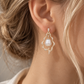 18K gold natural diamond and baroque pearl drop earrings featuring luminous white baroque pearls framed by an ornate pavé diamond design.