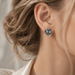 18K gold natural diamond and dark baroque pearl stud earrings featuring a sculptural pearl center accented with a delicate row of sparkling diamonds.