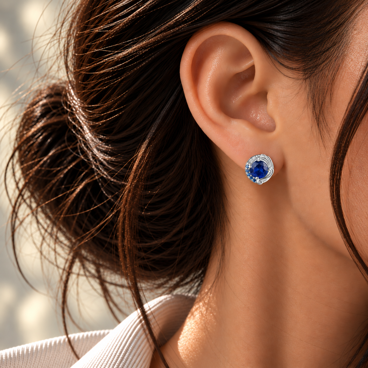18K white gold Le Grand Bleu stud earrings featuring deep natural blue sapphires accented with a gradient sapphire halo and sparkling natural colorless diamonds in a wave-inspired design, as featured in British Vogue.