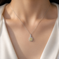 Close-up model shot of a 0.25 carat yellow diamond halo pendant necklace in white gold, featuring a cushion-cut yellow center stone surrounded by yellow and white diamonds, worn on the neckline with the model’s face not visible.