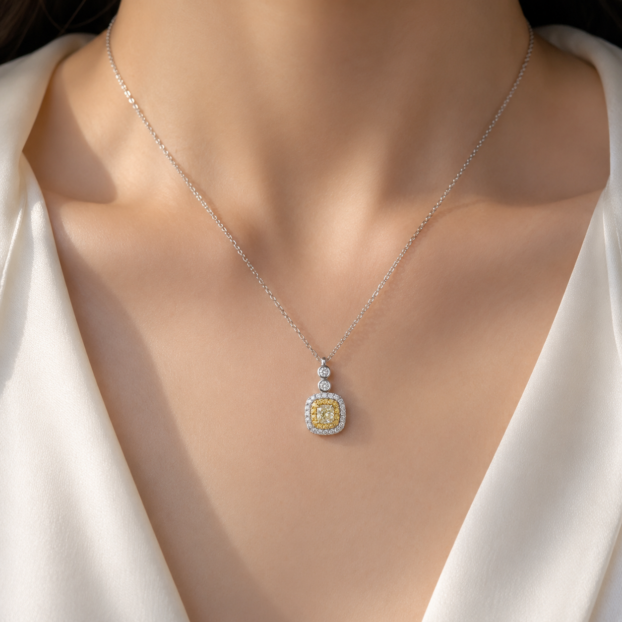 Close-up model shot of a 0.25 carat yellow diamond halo pendant necklace in white gold, featuring a cushion-cut yellow center stone surrounded by yellow and white diamonds, worn on the neckline with the model’s face not visible.