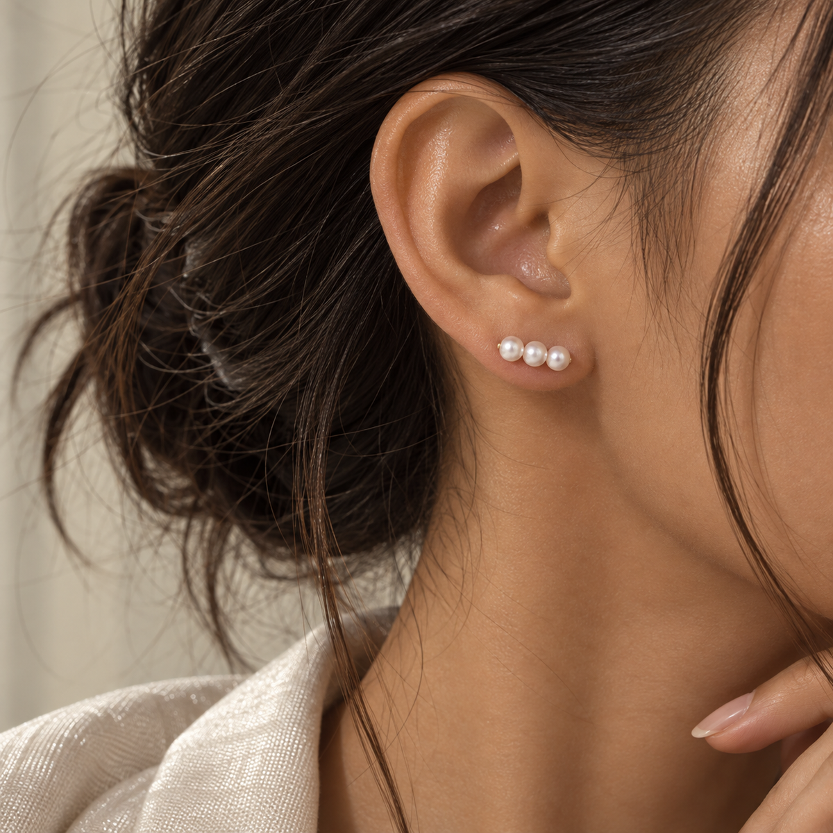 18K gold Akoya pearl stud earrings featuring three graduated saltwater Akoya pearls in a delicate linear design.