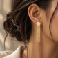 Italian 18K gold tassel earrings featuring a textured round stud with cascading fine gold chains in an elegant statement design.