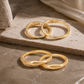 18K gold custom couple rings displayed on a textured stone, beautifully highlighting the secret MY and BX inner band engravings.