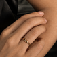 Lifestyle shot of a woman wearing a minimalist 18K gold wave matching band on her ring finger.