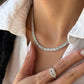 A model showcasing the Baguette Cut Superior Diamond Necklace paired with a matching statement diamond ring. The ring, worn on the hand resting against her white shirt, features a brilliant cluster center and baguette band that perfectly complements the diamond tennis necklace.
