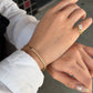 A model showcasing the 18K Natural Diamond Half Paperclip & Tennis Bracelet on her wrist, paired with a stunning pear-shaped diamond ring worn on the hand. The yellow gold jewelry set is styled elegantly against a white collared shirt, perfect for everyday luxury.