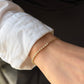 A model wearing the 18K Natural Diamond Half Paperclip & Tennis Bracelet in yellow gold, styled with a crisp white shirt. This modern fine jewelry piece features a seamless hybrid design, transitioning from a classic row of brilliant-cut diamonds to sleek gold paperclip chain links.