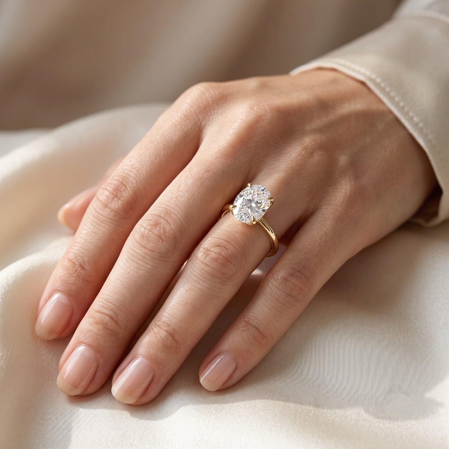 Lifestyle view of a 2.01 carat oval lab-grown diamond solitaire engagement ring crafted in 18K yellow gold, gracefully modeled on a left ring finger.