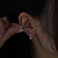 18K yellow gold lab-grown heart diamond drop earring worn on the ear, with its matching earring held beside it.