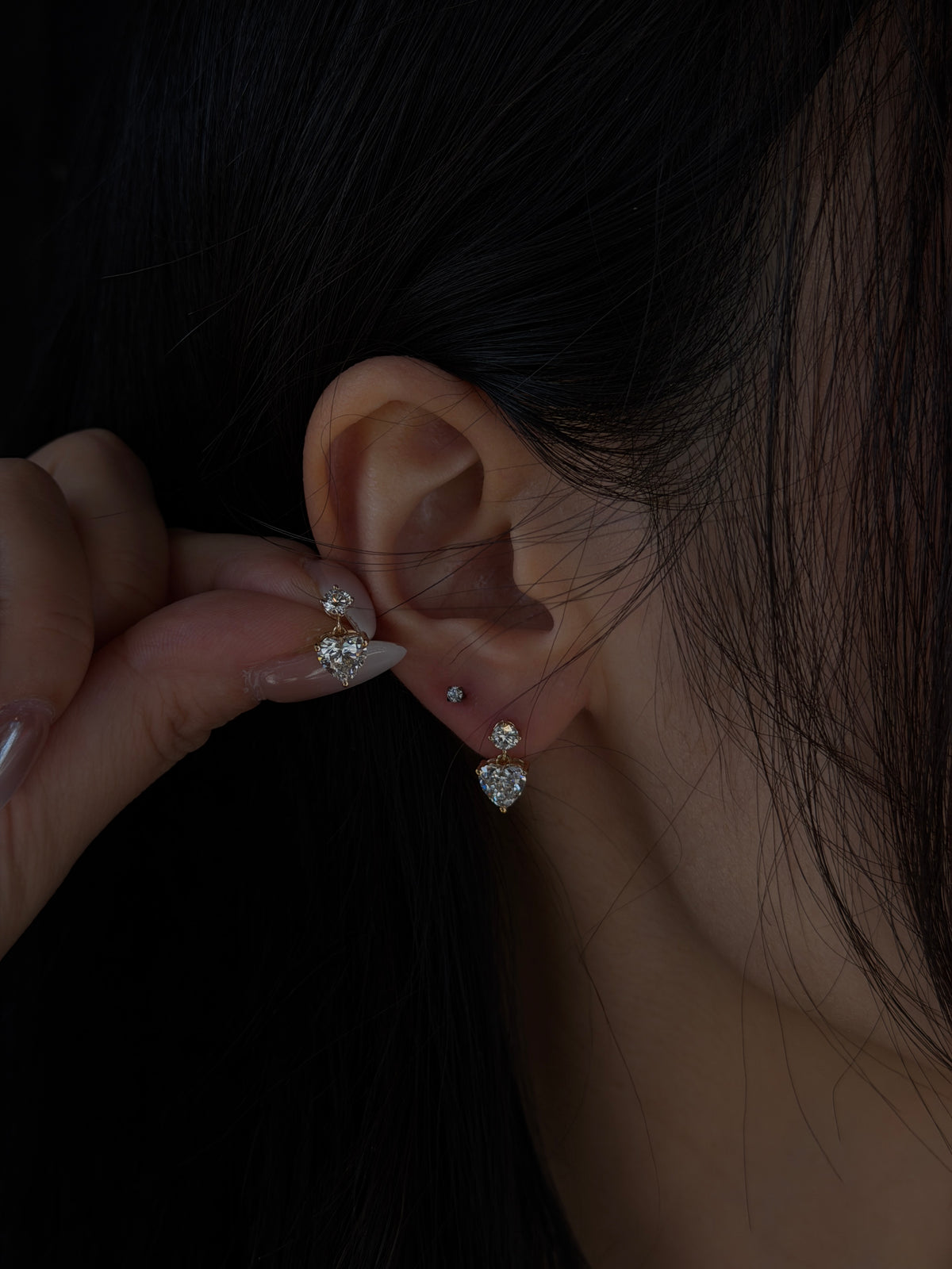 18K yellow gold lab-grown heart diamond drop earring worn on the ear, with its matching earring held beside it.