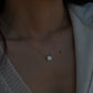 Close-up of a woman wearing an 18K gold bezel set diamond necklace resting elegantly on her collarbone.