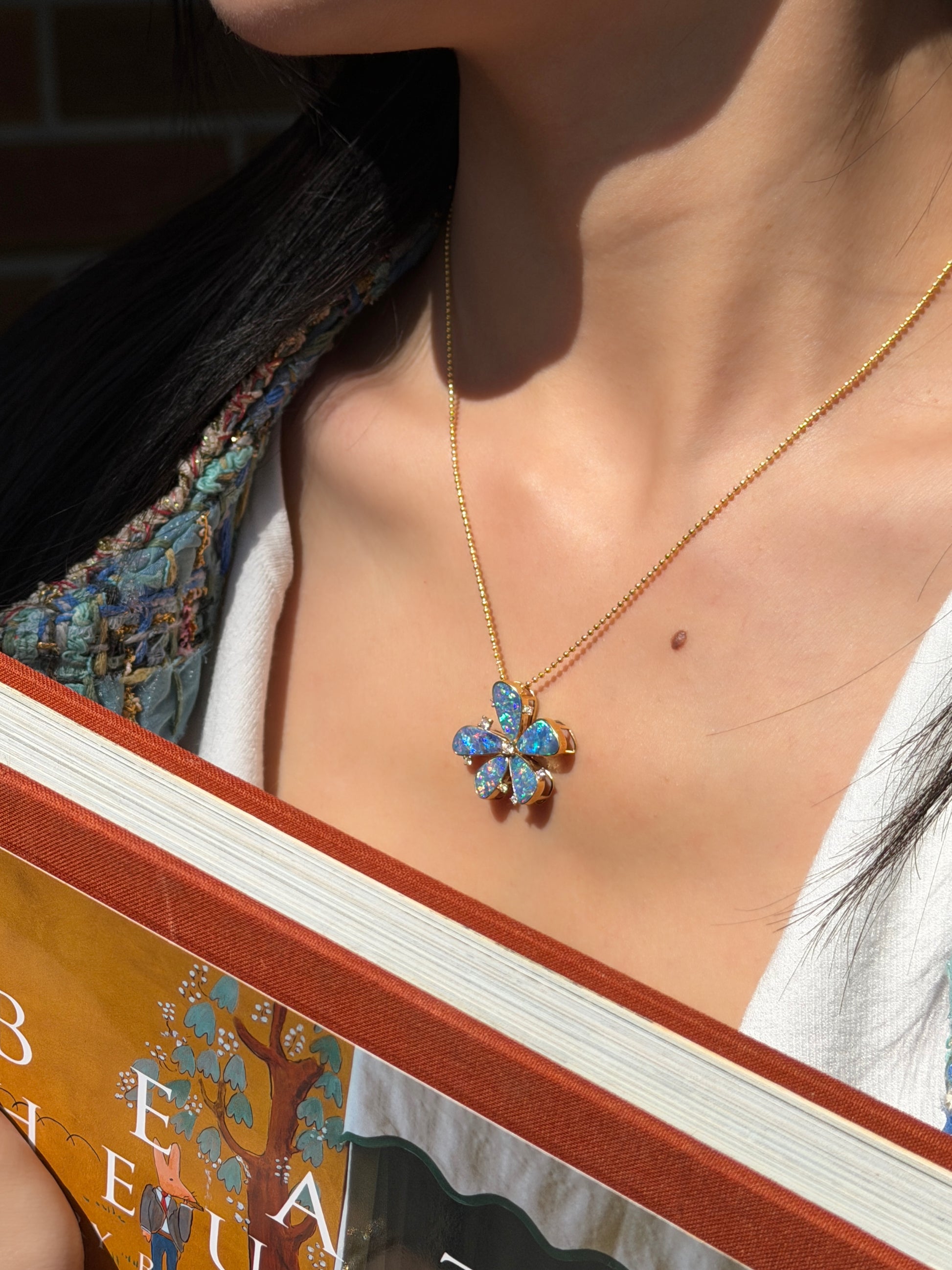 Alt Text: > Large floral pendant featuring five natural blue-green opals set in 18K yellow gold with diamond accents on a gold ball chain.