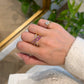 18K yellow gold Azure Tide ring with rows of pink sapphires and shimmering diamonds in a wave-inspired crossover band.