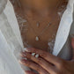Close-up of a model wearing a 1-carat pear-cut lab-grown diamond pendant necklace on a silver chain, layered with a small diamond cross necklace and matching pear-shaped diamond stud earrings.