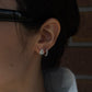 Diamond hoop earring featuring a pear-shaped diamond centerpiece paired with a curved row of round brilliant-cut diamonds, styled on the ear.
