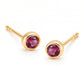 Pair of 18K yellow gold stud earrings featuring bezel-set round pink tourmaline gemstones.