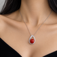 18K white gold pendant necklace featuring a polished natural red coral sphere framed by a teardrop-shaped halo of sparkling natural diamonds.