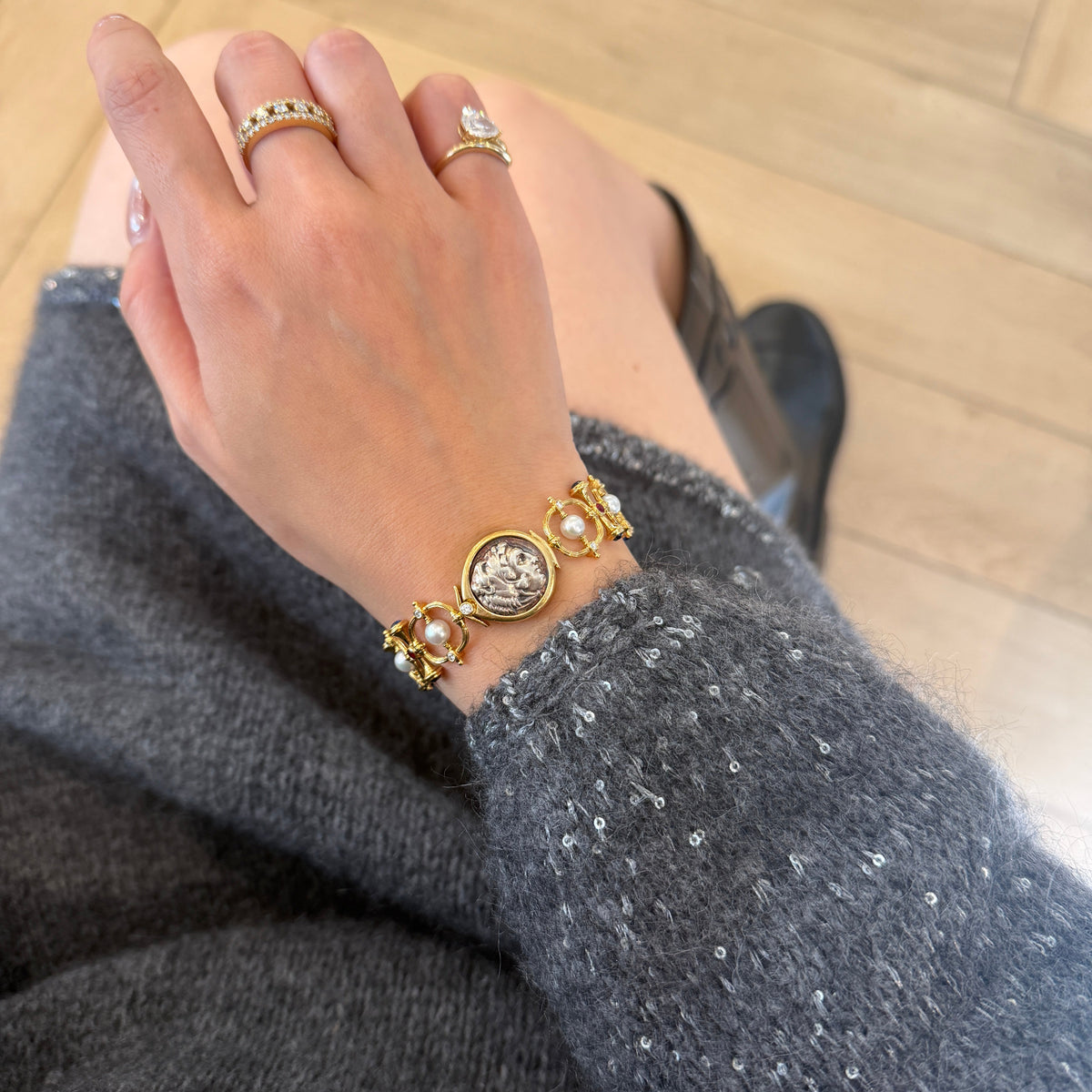 18K gold bracelet featuring lustrous white pearls, natural ruby and sapphire accents, sparkling diamond details, and a vintage-inspired coin centerpiece.
