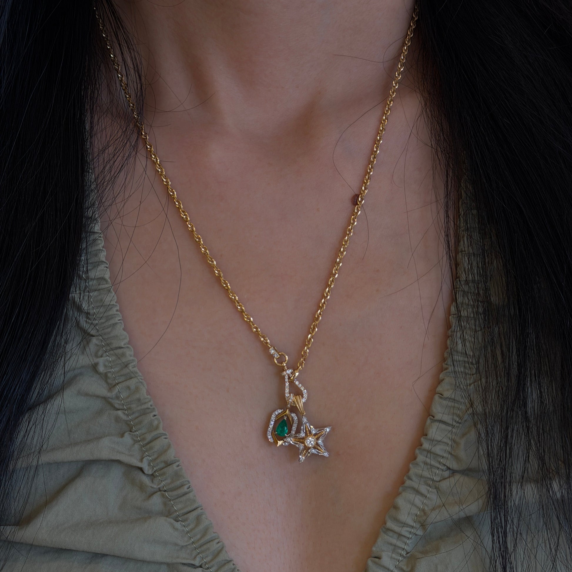 18K gold natural emerald and diamond pendant paired with an 18K gold natural diamond star pendant, styled together on a versatile 18K gold diamond chain.